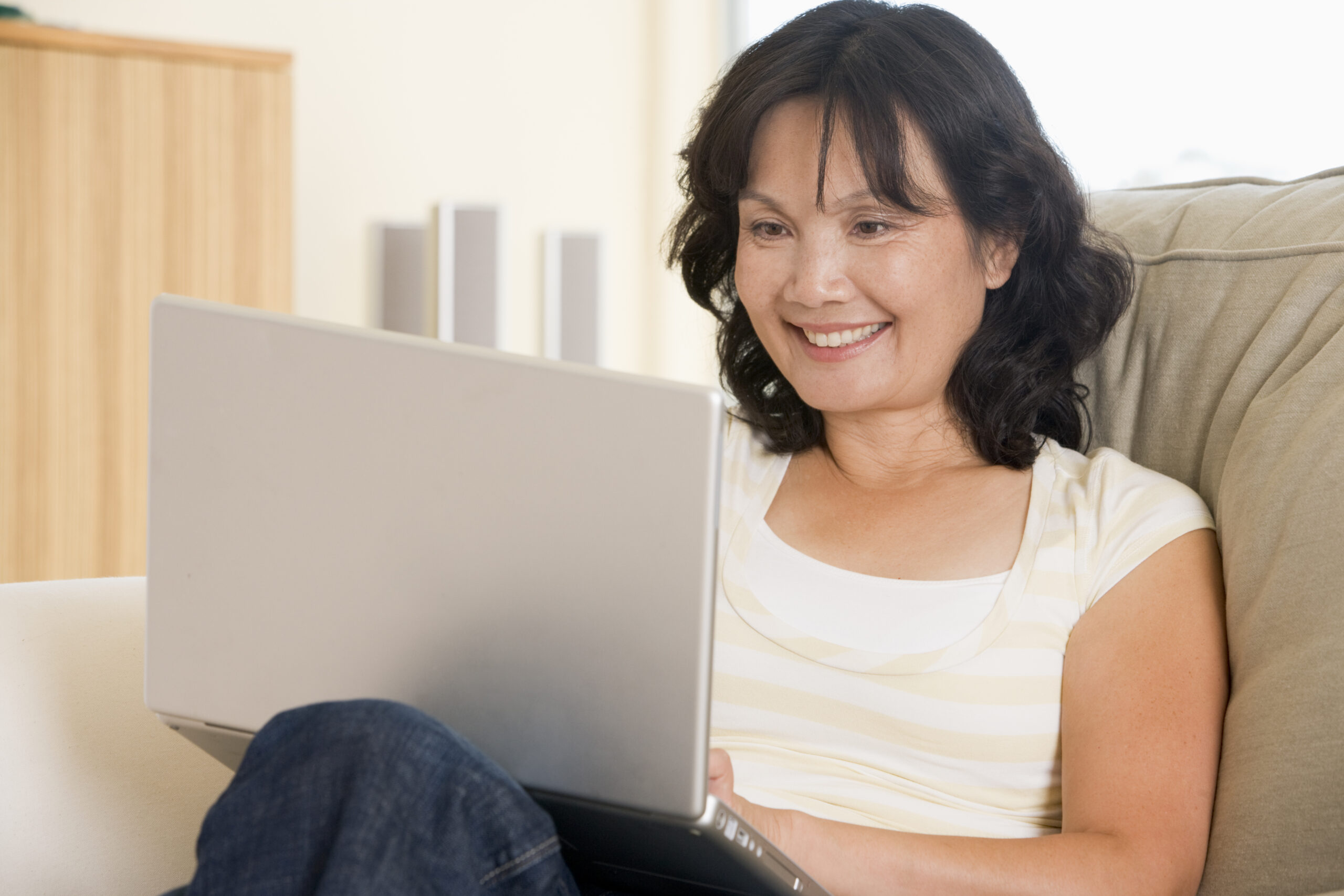 Woman in living room using laptop and smiling